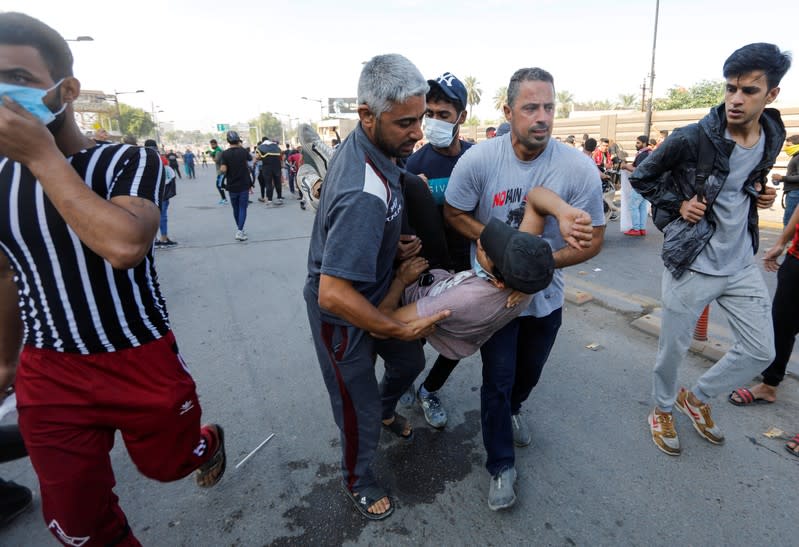 Demonstrators carry a man who fainted from the effect of tear gas during a protest over corruption, lack of jobs, and poor services, in Baghdad