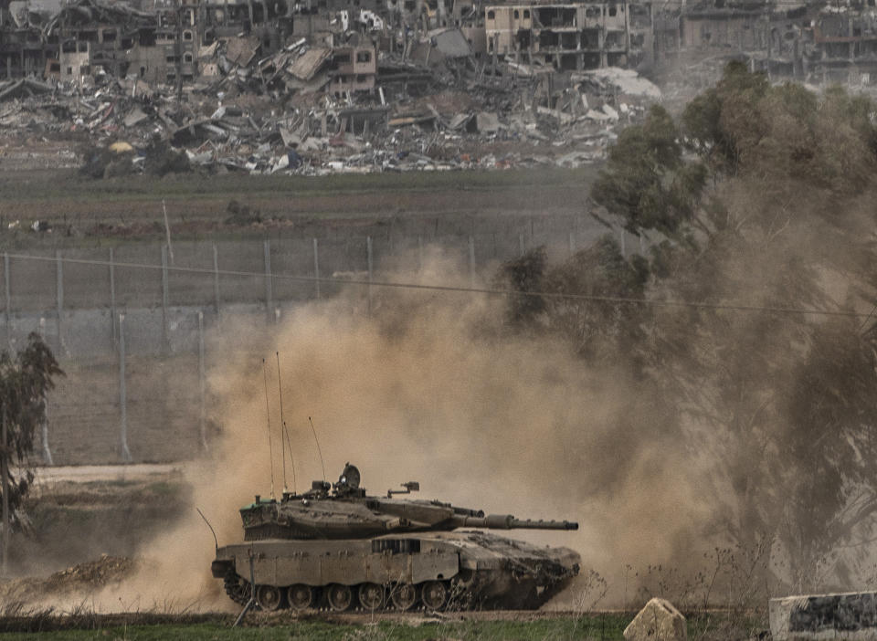 An Israeli army tank moves near the Gaza Strip border, in southern Israel, Saturday, Dec. 23, 2023. The army is battling Palestinian militants across Gaza in the war ignited by Hamas' Oct. 7 attack into Israel. Smoke from an Israeli bombardment is seen in background. (AP Photo/Tsafrir Abayov)