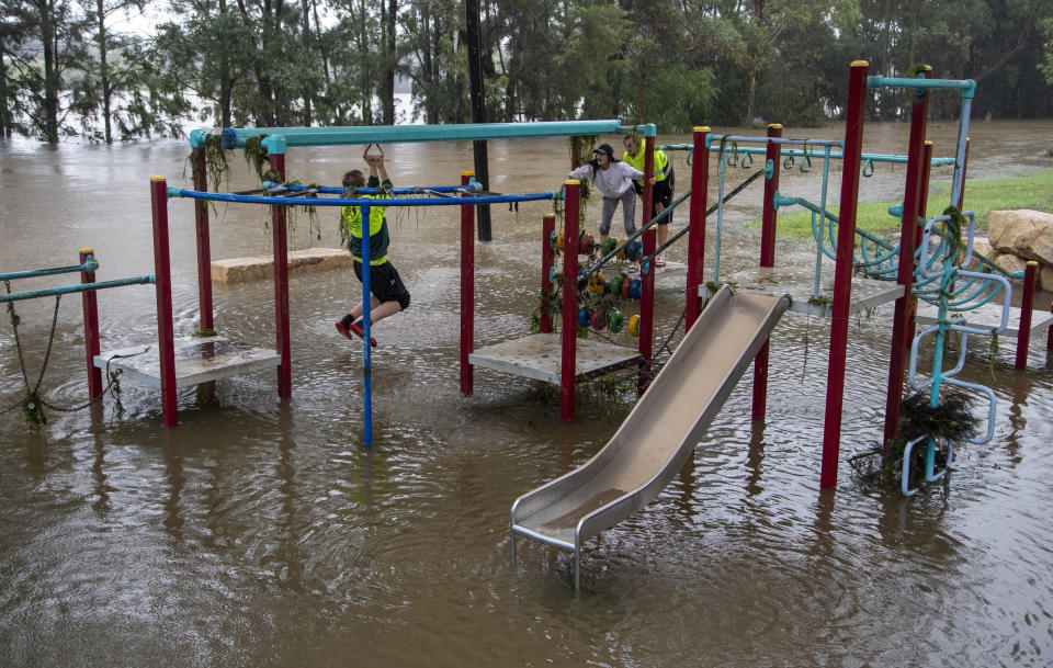 People play on equipment at a playground on the banks of the Nepean River at Jamisontown on the western outskirts of Sydney Monday, March 22, 2021. Australia's most populous state of New South Wales has issued more evacuation orders following the worst flooding in decades. (AP Photo/Mark Baker)