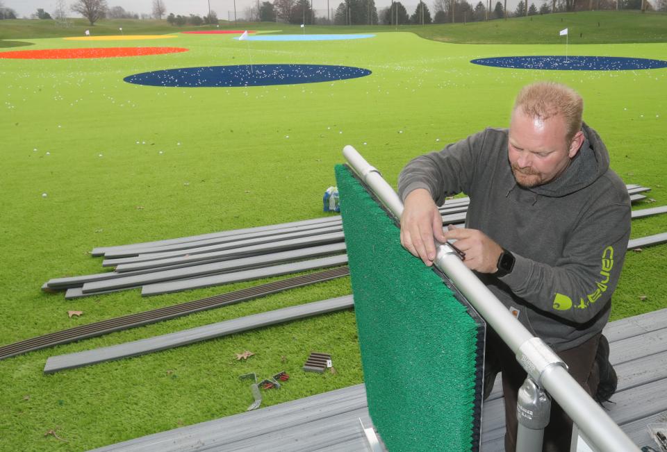 BJ Lewis of Power Tree installs part of the automatic tee up machine used at BIgShots Golf  in Akron.