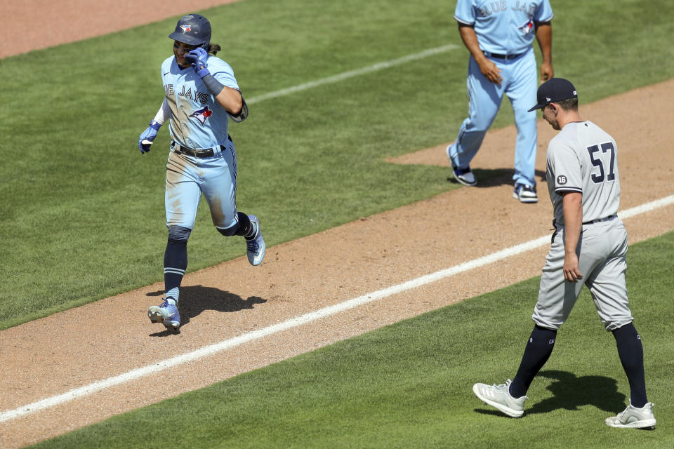 Toronto Blue Jays' Bo Bichette, left, comes in to score on his game-winning home run off of New York Yankees relief pitcher Chad Green (57) during the ninth inning of a baseball game Wednesday, April 14, 2021, in Dunedin, Fla. The Blue Jays won 5-4. (AP Photo/Mike Carlson)