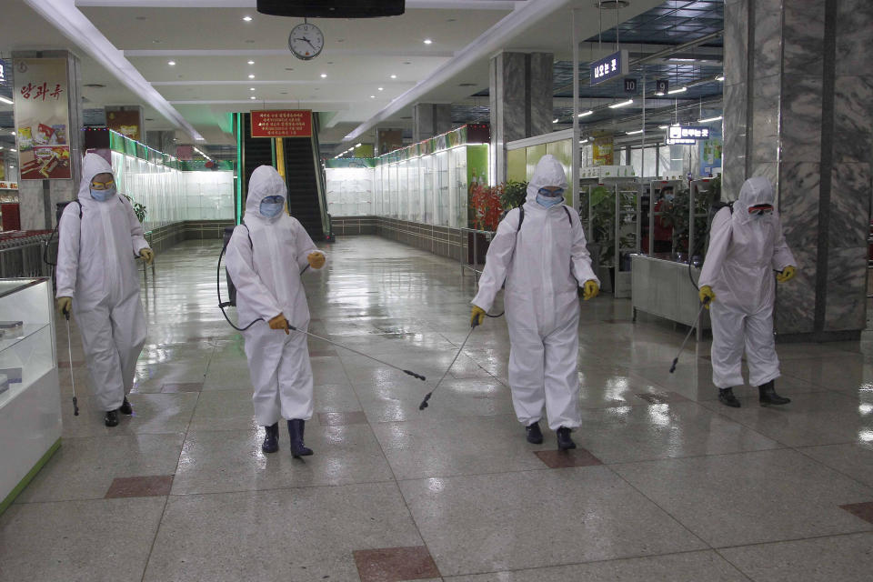 FILE - In this Dec. 28, 2020, file photo, staff of the Pyongyang Department Store No. 1 disinfect the store to help curb the spread of the coronavirus before it opens in Pyongyang, North Korea. A North Korean website says the country will not participate in the Tokyo Olympics because of the coronavirus pandemic. The Sports in DPR Korea website said Tuesday, April 6, 2021 the decision was made during a national Olympic Committee meeting on March 25 where members prioritized protecting athletes from the “world public health crisis caused by COVID-19.” (AP Photo/Jon Chol Jin, File)