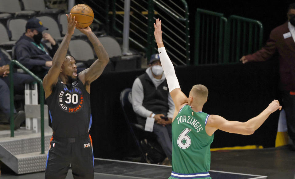 New York Knicks forward Julius Randle (30) attempts a 3-point shot against Dallas Mavericks center Kristaps Porzingis (6) during the first half of an NBA basketball game Friday, April 16, 2021, in Dallas. (AP Photo/Ron Jenkins)