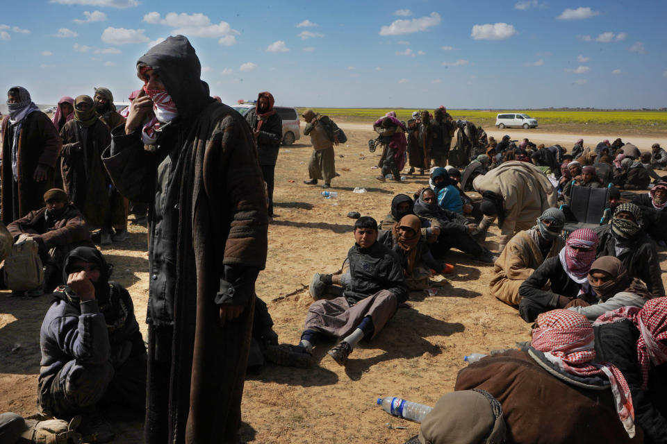 Men wait to be screened after being evacuated out of the last territory held by Islamic State militants outside Baghouz, Syria, Wednesday, March 6, 2019. Since Friday, IS has put up desperate resistance to renewed pounding by the U.S.-backed Syrian Democratic Forces aiming to take the tiny pocket on the Euphrates River near the Iraqi border.(AP Photo/Andrea Rosa)