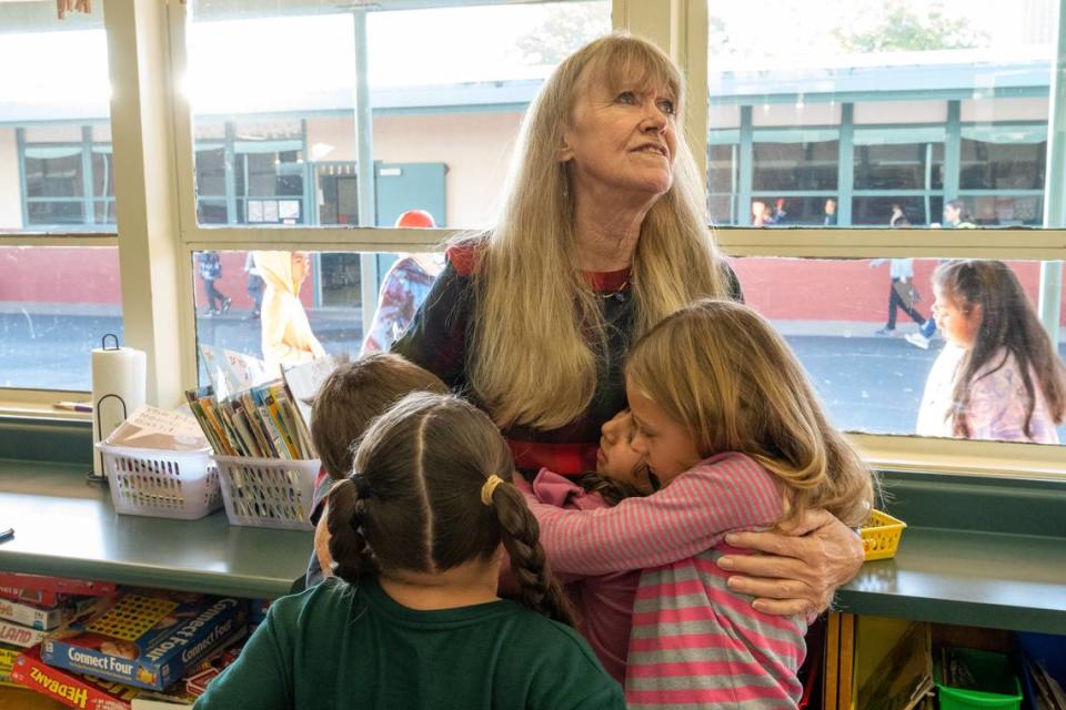 Donja Garvey, of the non-profit My Mother’s Voice, embraces children after a book and blanket give-a-way at Cirby Elementary School in Roseville last month.