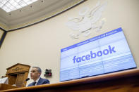 A list of settlements, violations and breaches scrolls over Facebook's logo on a screen behind David Marcus, CEO of Facebook's Calibra digital wallet service, left, as he speaks during a House Financial Services Committee hearing on Facebook's proposed cryptocurrency on Capitol Hill in Washington, Wednesday, July 17, 2019. (AP Photo/Andrew Harnik)