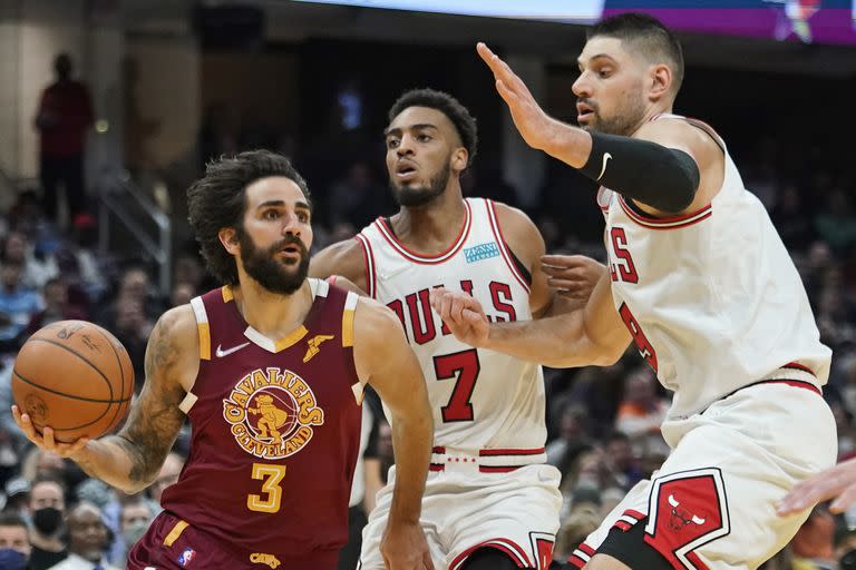 ARCHIVO- Ricky Rubio (3), de los Cavaliers de Cleveland, enfila hacia la canasta ante la marca defensiva de Troy Brown Jr. (7) y Nikola Vucevic (9), de los Bulls de Chicago, en la segunda mitad del juego de baloncesto de la NBA, el miércoles 8 de diciembre de 2021, en Cleveland. Más de un año después de desgarrarse un ligamento de la rodilla y ser sometido a cirugía, se espera que Rubio debute en la temporada en jueves 12 de enero, cuando Cleveland visite a Trail Blazers de Portland. (AP Foto/Tony Dejak, Archivo)