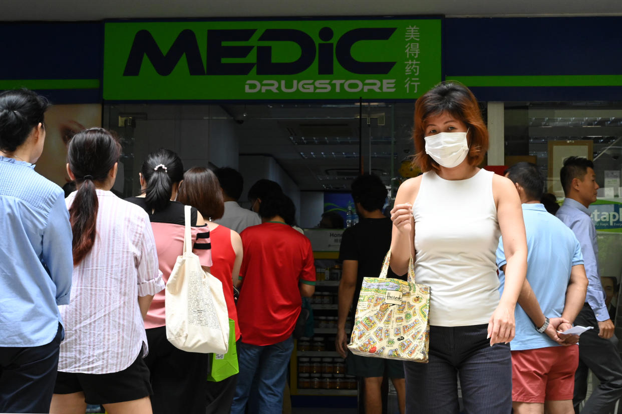 People queue outside a pharmacy to purchase protective face masks, thermometers and hand sanitisers in Singapore on 29 January, 2020. (PHOTO: AFP via Getty Images)