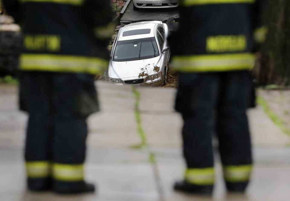 Firefighters look at a car sitting on the edge of a sinkhole in the Charles Village neighborhood of Baltimore, Wednesday, April 30, 2014, as heavy rain moves through the region. Road closures have been reported due to flooding, downed trees and electrical lines elsewhere in the Mid-Atlantic. The National Weather Service issued flash flood warnings through Wednesday afternoon in Washington, northern Virginia and central Maryland. (AP Photo)