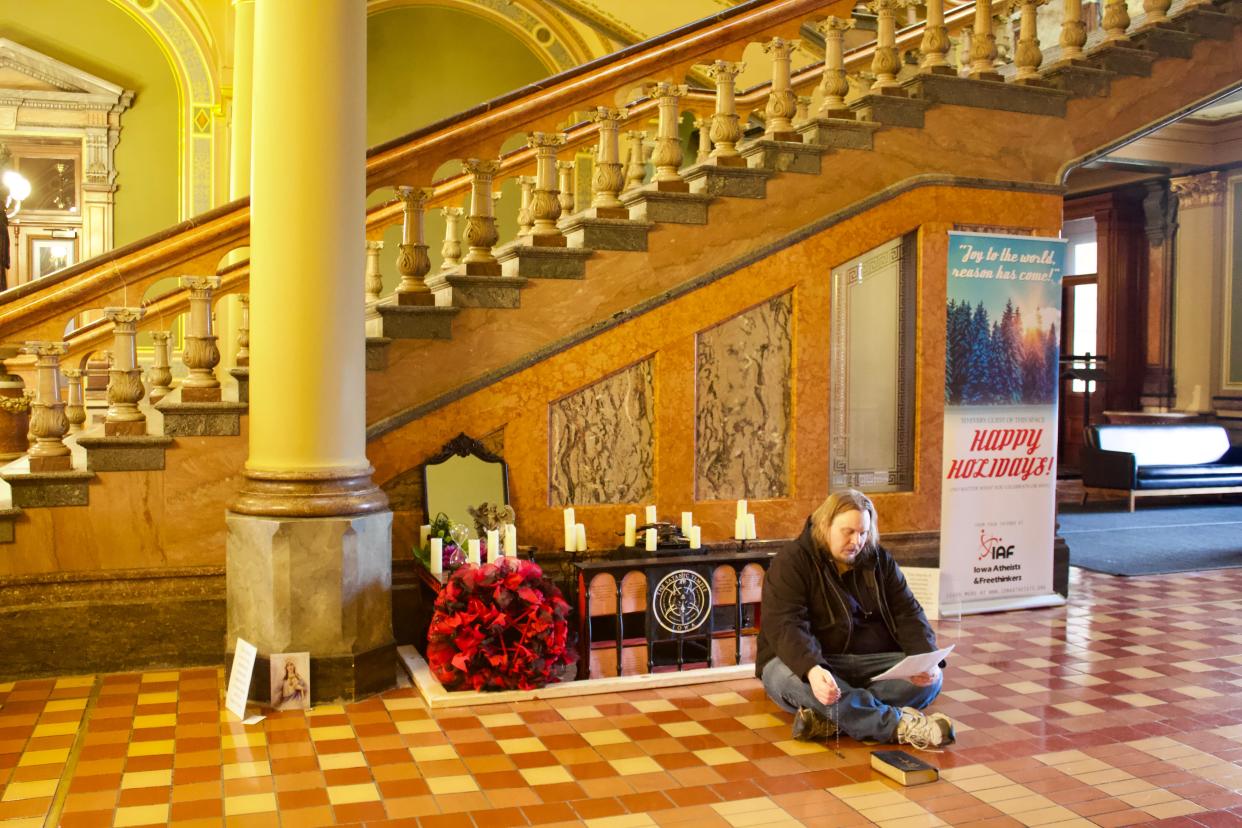 Man seen praying in front of the vandalized satanic display at the Iowa State Capitol.
