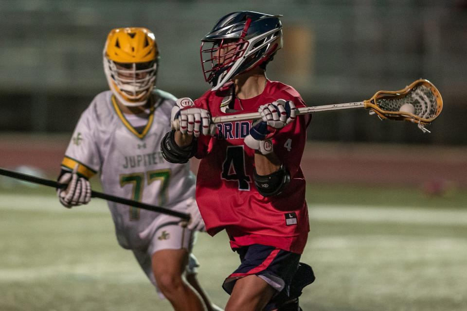 The Jupiter Community High School Warriors hosted the Oxbridge Academy Thunderwolves in a Florida High School Athletic Association boys high school lacrosse game at the school in Jupiter, Fla., on March 26, 2024. The Warriors won 12-5 over the Thunderwolves. Ryan Stowell (4) carries the ball during the game.