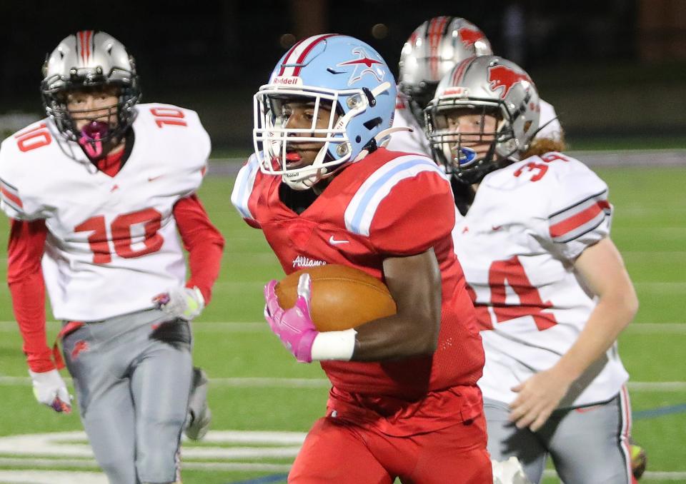 Alliance's Ramhir Hawkins races away from Minerva defenders on his way to a first-quarter touchdown, Friday, Oct. 13, 2023, at Kehres Stadium.