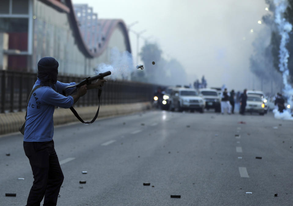 A policeman fires tear gas to disperse supporters of Pakistan's key opposition party marching in Islamabad, Pakistan, Wednesday, May 25, 2022. Pakistani authorities blocked off all major roads into the capital Islamabad on Wednesday, after a defiant former Prime Minister Imran Khan said he would march with demonstrators to the city center for a rally he hopes will bring down the government and force early elections. (AP Photo/Rahmat Gul)