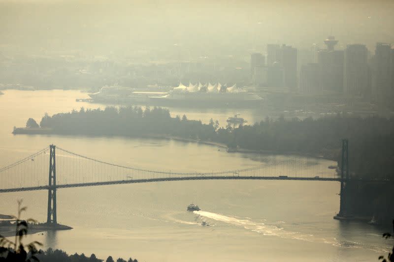A boat passes under the Lions Gate bridge to enter Vancouver Harbour, shrouded in a haze a wildfire smoke