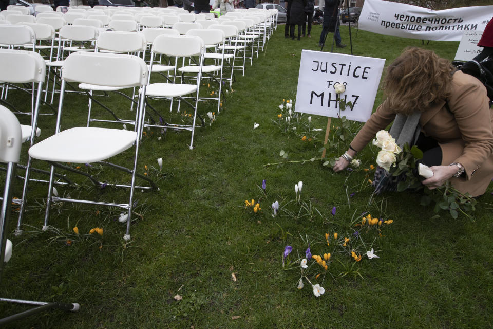 A woman places a rose next to 298 empty chairs, each chair for one of the 298 victims of the downed Malaysia Air flight MH17, in a park opposite the Russian embassy in The Hague, Netherlands, Sunday, March 8, 2020. A missile fired from territory controlled by pro-Russian rebels in Ukraine in 2014, tore the MH17 passenger jet apart killing all 298 people on board. United by grief across oceans and continents, families who lost loved hope that the trial which starts Monday March 9, 2020, will finally deliver them something that has remained elusive ever since: The truth. (AP Photo/Peter Dejong)