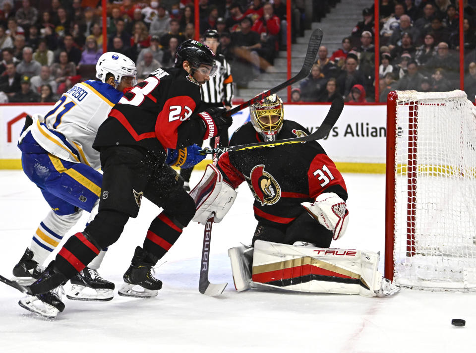 Ottawa Senators goaltender Anton Forsberg (31) watches the puck as defenseman Travis Hamonic and Buffalo Sabres right wing Kyle Okposo chase the rebound during the first period of an NHL hockey game in Ottawa, Ontario, Sunday, Jan. 1, 2023. (Justin Tang/The Canadian Press via AP)