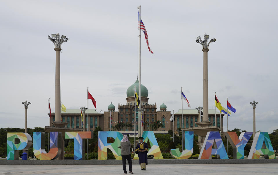 Women take pictures in front of the prime minister's office building in Putrajaya, Malaysia, Friday, Oct. 23, 2020. Malaysian opposition leader Anwar Ibrahim said Friday he was concerned about reports that Prime Minister Muhyiddin Yassi may invoke emergency laws to suspend Parliament and stymie bids to oust his government. (AP Photo/Vincent Thian)