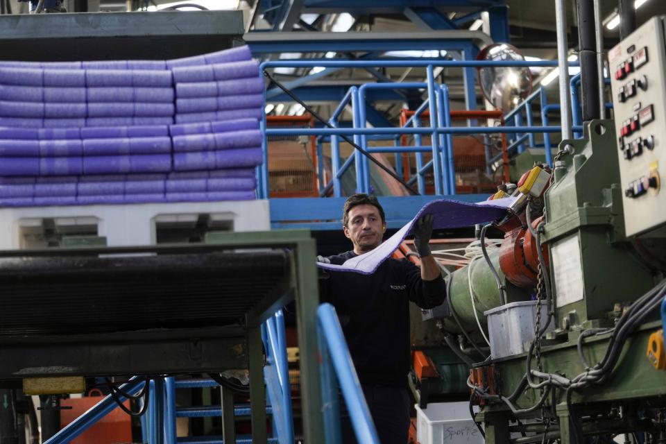 A worker checks an automatic machine composing the surface of the athletics track, at the Mondo factory, in Alba, northern Italy, Wednesday, March 13, 2024. The athletics track for the upcoming Paris Olympics is being produced by the Mondo company at its factory in northern Italy. The track is made in portions, rolled up and then will be transported to the Stade de France, where it will be installed over the next month. (AP Photo/Luca Bruno)