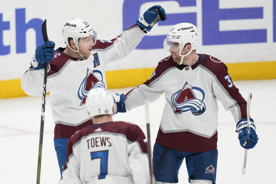 Colorado Avalanche center Nathan MacKinnon (29) celebrates with defenseman Devon Toews (7) and left wing J.T. Compher (37) after scoring during overtime of an NHL hockey game in Anaheim, Calif., Sunday, April 9, 2023. The Avalanche won 5-4. (AP Photo/Ashley Landis)