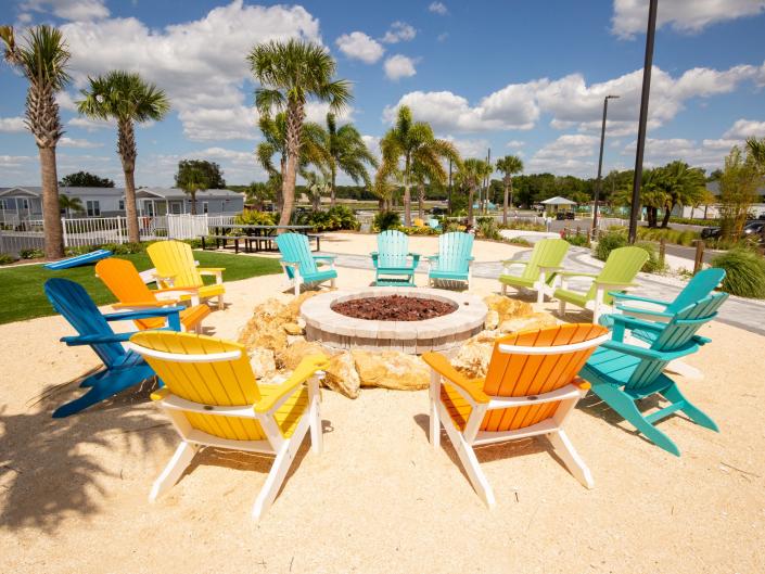 Colorful lounge chairs surrounding a fire pit.