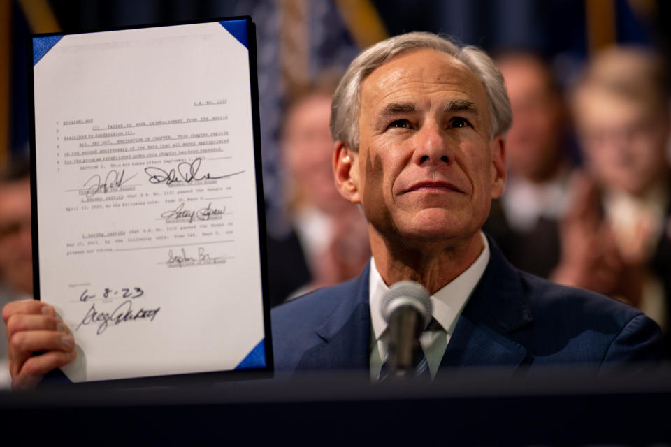 Texas Gov. Greg Abbott holds up signed legislation.