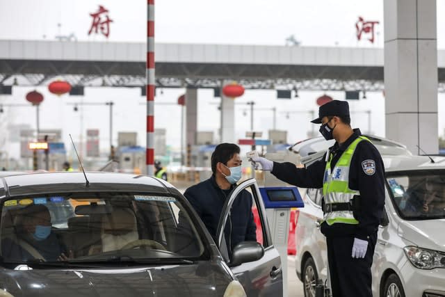 A policeman uses a digital thermometer to take a driver’s temperature at a checkpoint at a highway toll gate in Wuhan in central China’s Hubei Province 