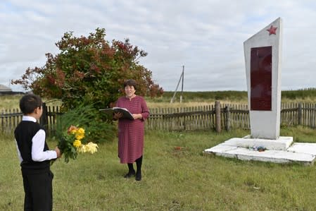 Ravil Izhmukhametov de 9 años, y su profesora, Uminur Kuchukova, de 61 años, durante una ceremonia en su primer día de clases del año escolar junto a un Memorial nacional a la Segunda Guerra Mundial en Sibilyakovo, Rusia.