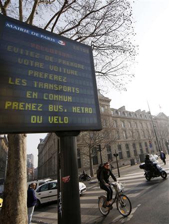 A Paris city information board which reads, "Pollution - Avoid taking your cars; prefer public transportations, take the bus, metro or your bicycle", is seen along a street in Paris March 14, 2014, as warm and sunny weather continues in France. Residents and visitors to Paris basking in a streak of unseasonable sunshine were also being treated with a dangerous dose of particles from car fumes that pushed air pollution to levels above other northern European capitals this week. REUTERS/Jacky Naegelen