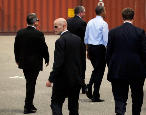 US President Barack Obama (blue shirt), surrounded by Secret Service agents walks away after a visit to the Port of Tampa, on April 13, in Tampa, Florida. The President visited Tampa while on his way to the Summit of the Americas in Colombia