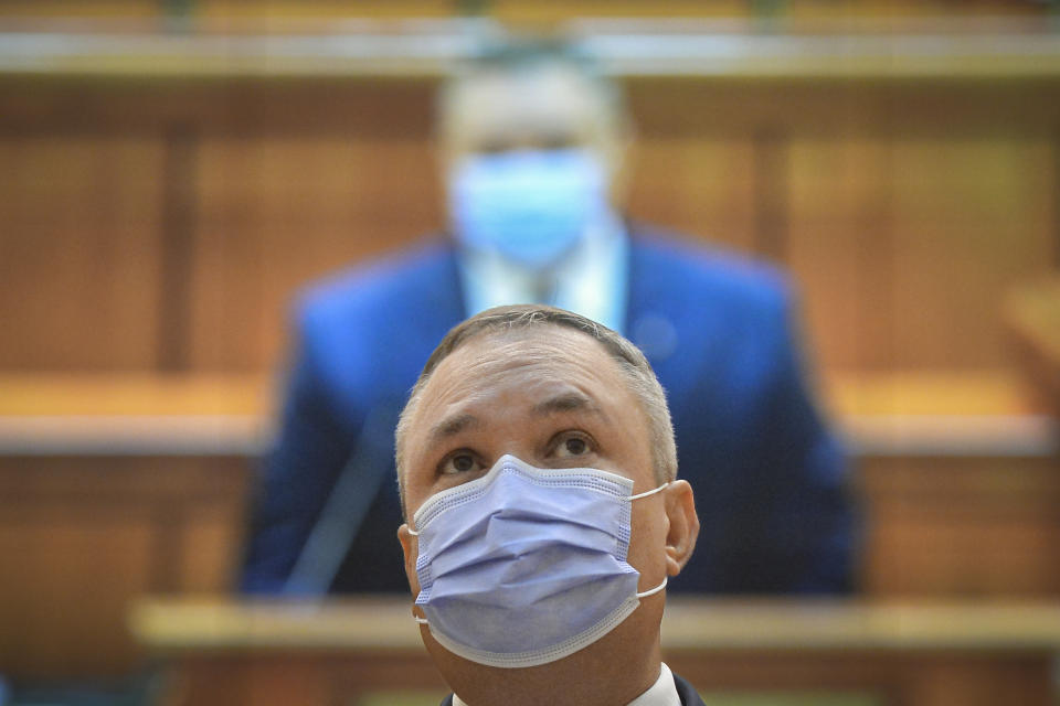 Romanian Prime Minister designate Nicolae Ciuca wears a mask before a parliament vote on his government team in Bucharest, Romania, Thursday, Nov. 25, 2021. Romanian lawmakers voted in favor of a new coalition government led by a Liberal former army general, which could usher in an end to a months-long political crisis in the Eastern European nation.(AP Photo/Alexandru Dobre)