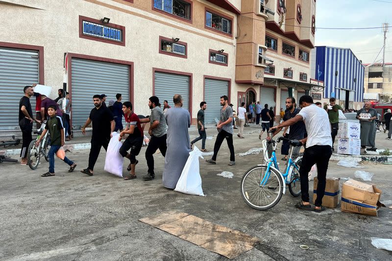 Palestinians carry food supplies near a United Nations Palestinian refugee agency (UNRWA) run warehouse in Khan Younis