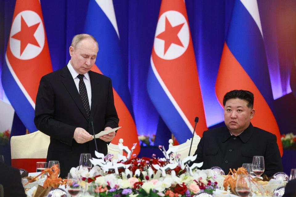 Putin, left, speaks as Kim listens to him during a state reception after their talks in Pyongyang, North Korea, on Wednesday (AP)