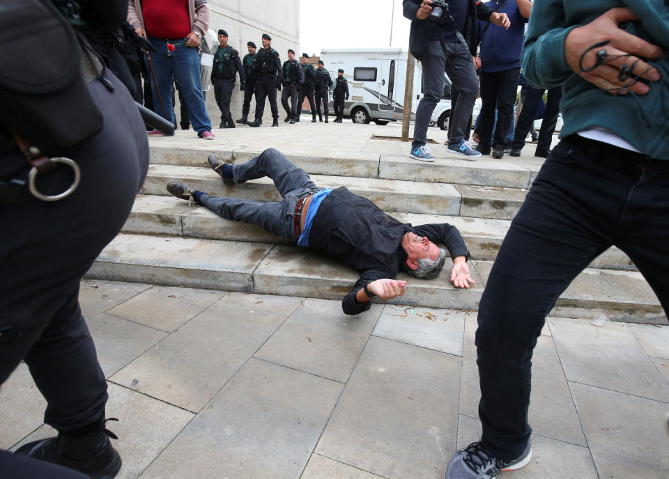 <p>A man falls to the ground during scuffles with Spanish Civil Guard officers outside a polling station for the banned independence referendum in Sant Julia de Ramis, Spain, Oct. 1, 2017. (Photo: Albert Gea/Reuters) </p>