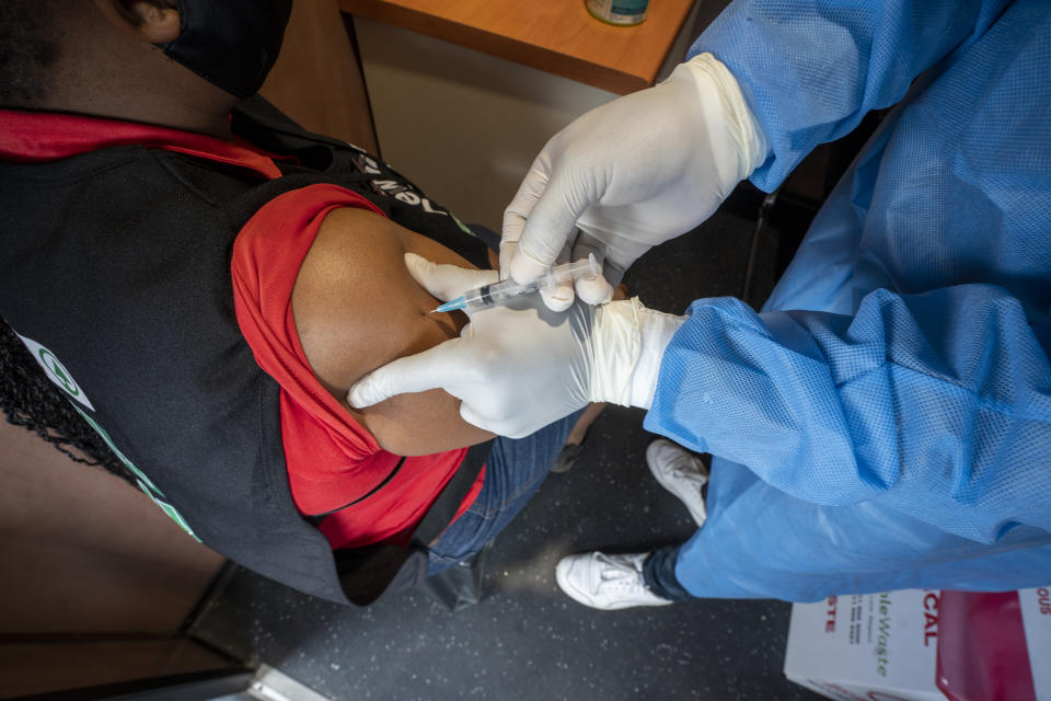 A patient receives her COVID-19 vaccine on a train at the Swartkops railroad yard outside Gqeberha, South Africa, Thursday Sept. 23, 2021. South Africa has sent a train carrying COVID-19 vaccines into one of its poorest provinces to get doses to areas where healthcare facilities are stretched. The vaccine train, named Transvaco, will go on a three-month tour through the Eastern Cape province and stop at seven stations for two weeks at a time to vaccinate people. (AP Photo/Jerome Delay)