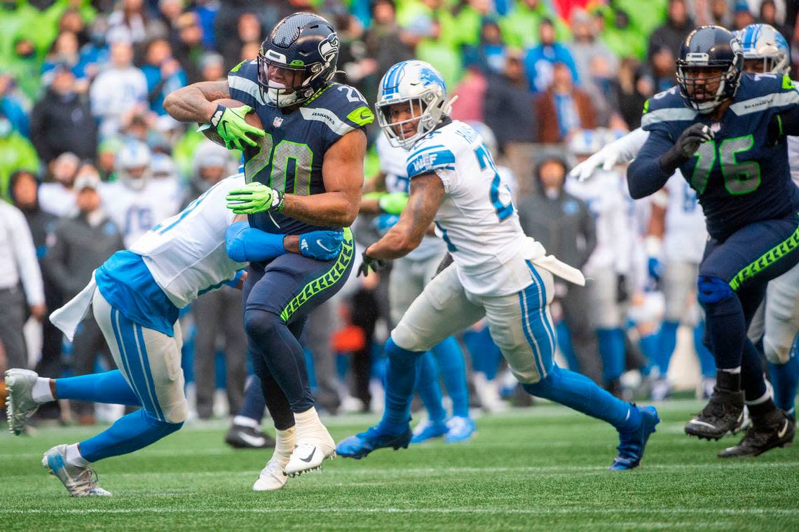 Seattle Seahawks running back Rashaad Penny (20) breaks through a tackle attempt by Detroit Lions free safety Tracy Walker (21) on his way to a rushing touchdown in the second quarter of an NFL game on Sunday, Jan. 2, 2022, at Lumen Field in Seattle.