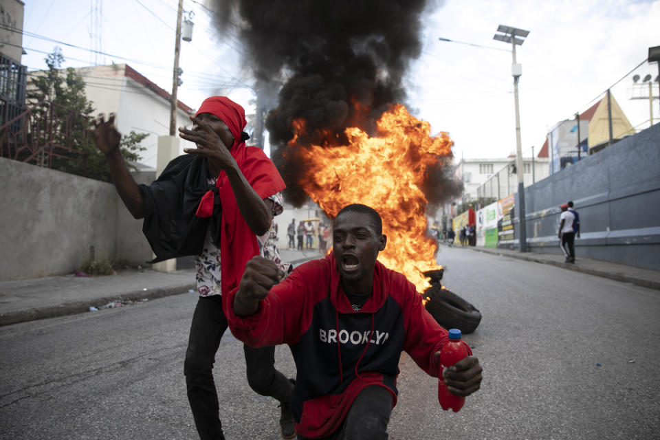 Protesters sing an anti-government song in front of a barricade of burning tires during a protest against the government in Port-au-Prince, Haiti, Friday, Nov. 18, 2022. (AP Photo/Odelyn Joseph)