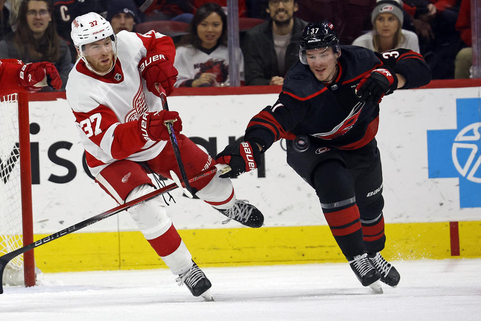 Detroit Red Wings' J.T. Compher, left, clears the puck past Carolina Hurricanes' Andrei Svechnikov, right, during the third period of an NHL hockey game in Raleigh, N.C., Friday, Jan. 19, 2024. (AP Photo/Karl B DeBlaker)