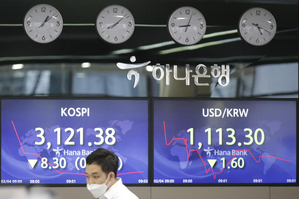 An employee of a bank walks by screens showing the Korea Composite Stock Price Index (KOSPI), left, and the foreign exchange rate between U.S. dollar and South Korean won at the foreign exchange dealing room in Seoul, South Korea, Thursday, Feb. 4, 2021. Asian shares mostly fell Thursday as caution set in over company earnings reports, recent choppy trading in technology stocks and prospects for more economic stimulus for a world battling a pandemic. (AP Photo/Lee Jin-man)