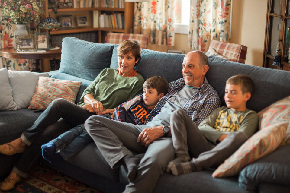 A family sitting on a couch and watching TV