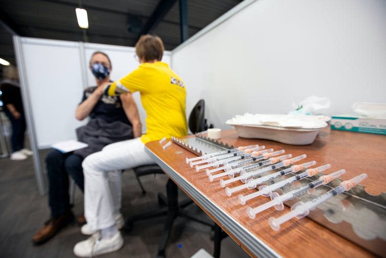 A man wearing facemask getting a COVID vaccine.