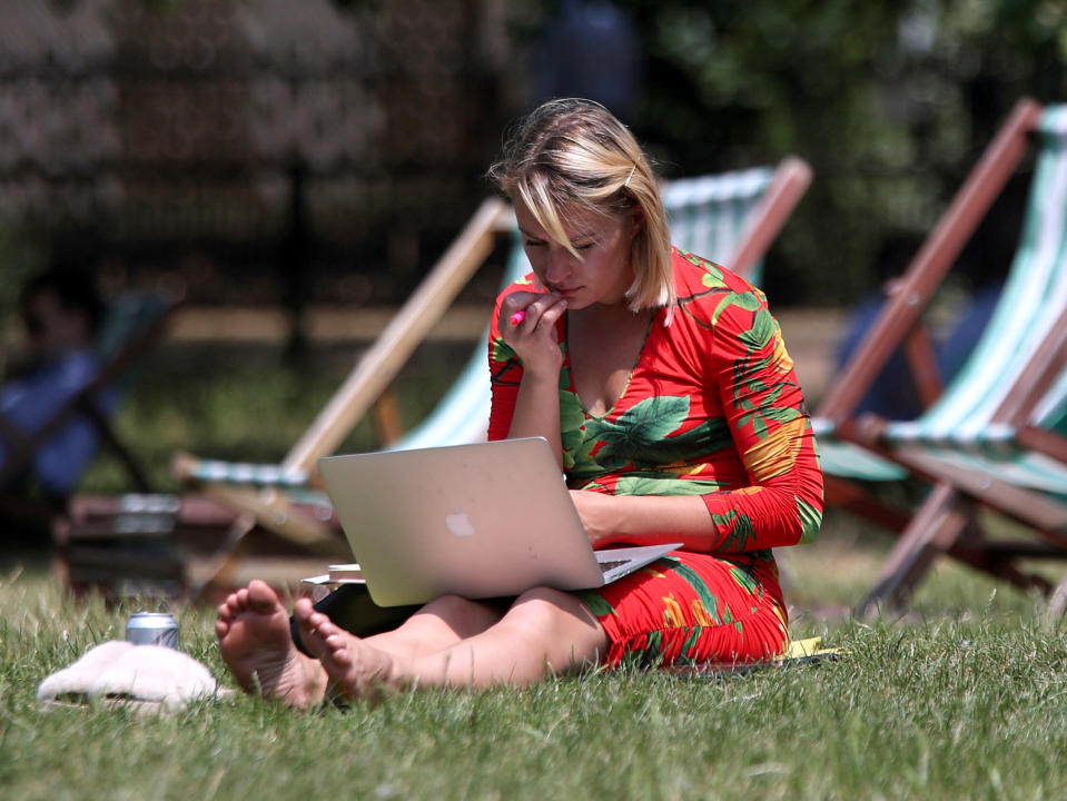 A woman working on a laptop in Green Park, London. Britons look set to enjoy the hottest temperatures of the year for the fourth day in a row this week, with the mercury predicted to soar to 32C (89.6F). (Photo by Yui Mok/PA Images via Getty Images)