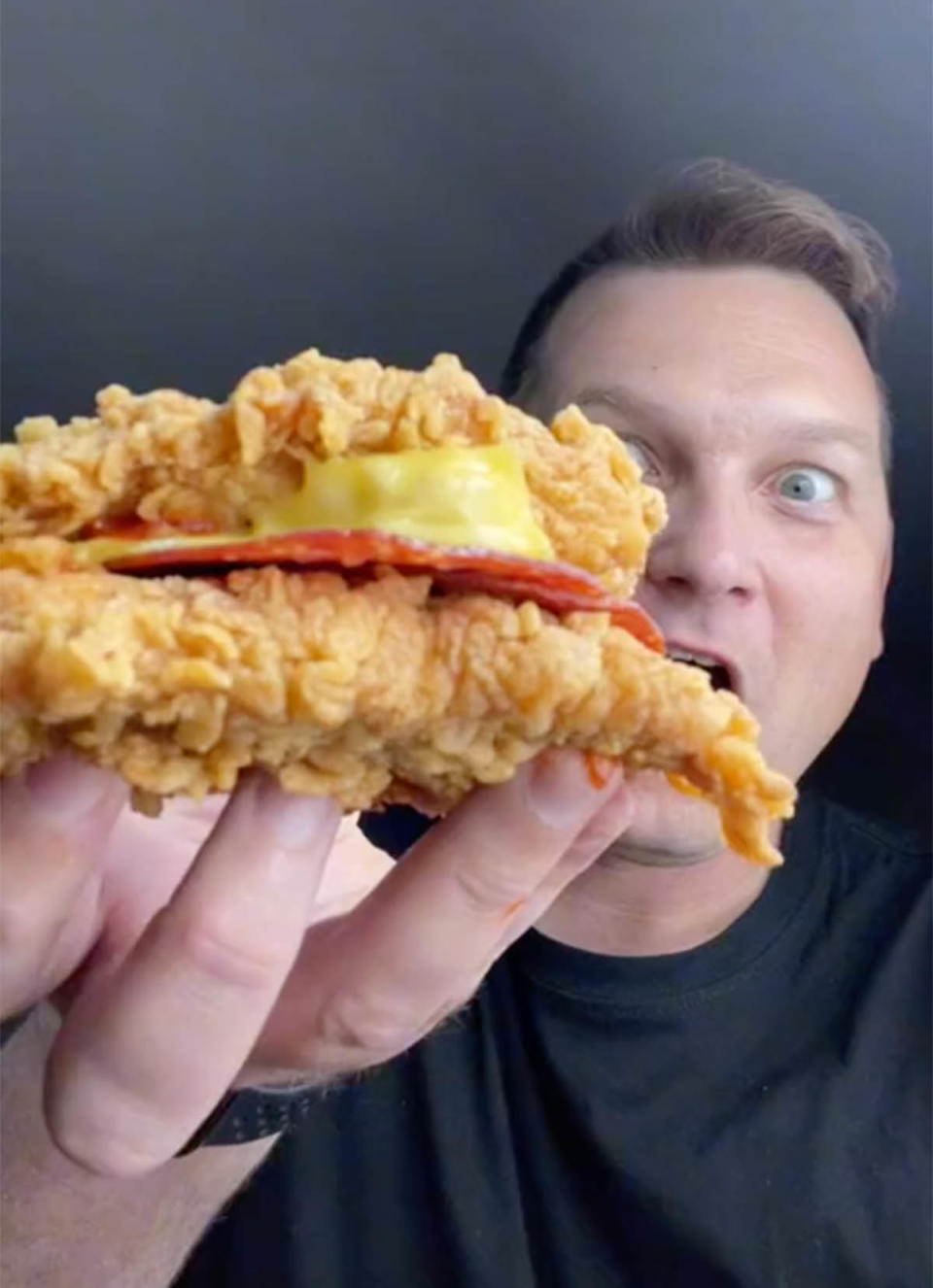 TikTok food reviewer @aussie_qbbq holding KFC's new menu item, the Pizza Double