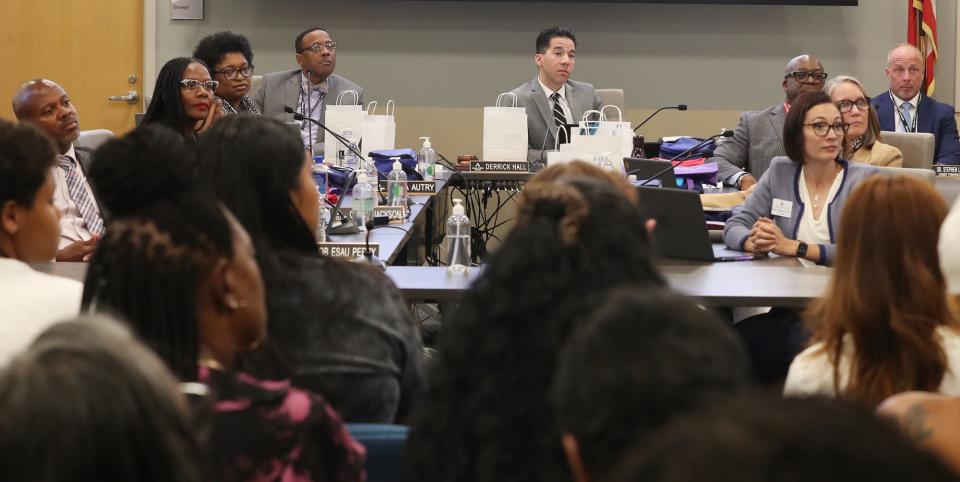 Akron Public Schools superintendent Michael Robinson, left school board president Derrick Hall, center, listen with the rest of the school board and staff to supporters of the I Promise School address the board during a meeting in Akron.