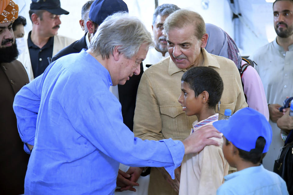 In this handout photo released by Pakistan Prime Minister Office, Prime Minister Shahbaz Sharif, center right, and U.N. Secretary-General Antonio Guterres, left, interact with children at a school set up at a flood relief camp in Jaffarabad, Pakistan, Saturday, Sept. 10, 2022. U.N. Secretary-General Antonio Guterres on Saturday toured Pakistan's flood-ravaged Sindh and Baluchistan provinces a day after saying the world is obligated to provide "massive" amounts of relief to the impoverished country. (Pakistan Prime Minister Office via AP)