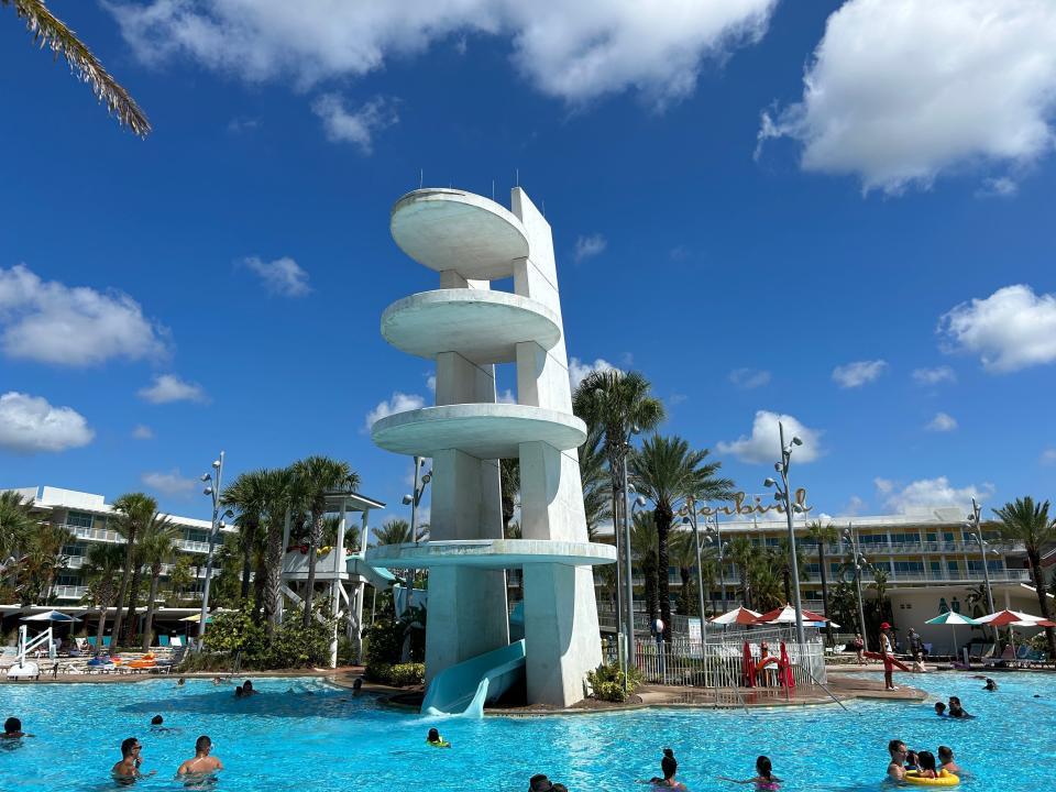 A pool at the Cabana Bay Beach Resort at Universal Orlando. There is a large waterslide and many guests enjoying the pool.