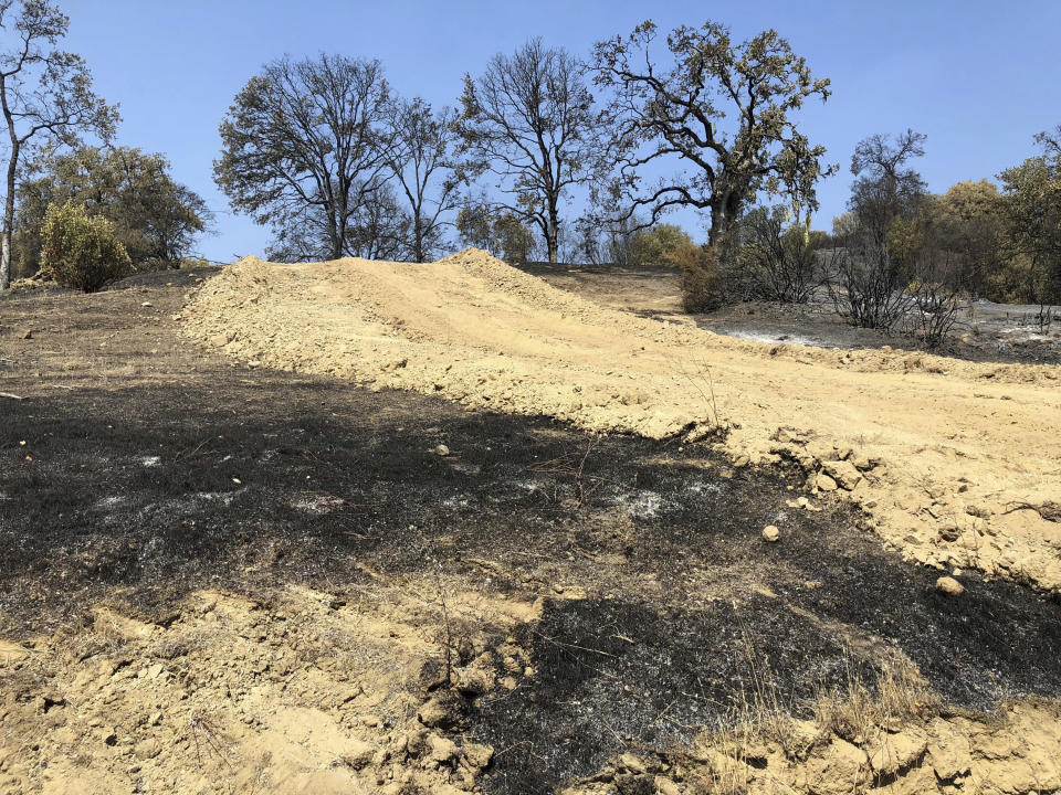 This photo taken Friday, Aug. 10, 2018 near Lakeport, Calif. shows a dirt path and dusty berms left behind when a bulldozer passed through private land in an effort to contain part of the largest wildfire on record in California. Even as flames continue chewing through forestland nearby, crews are working to repair the damage wrought not by flames but by firefighters trying to stop them. (AP Photo/Jonathan J. Cooper)