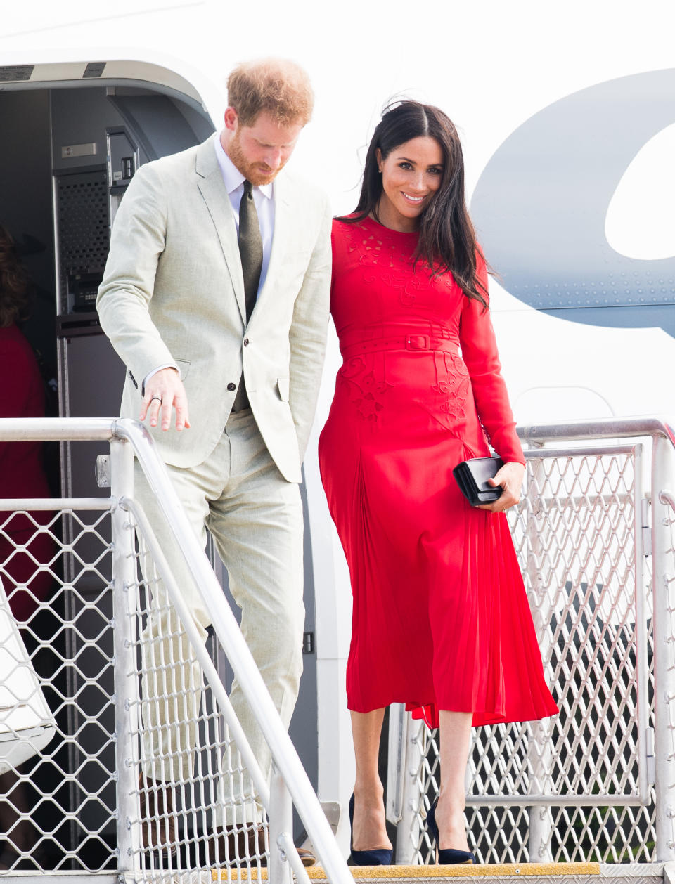 <p>C’est à sa descente de l’avion pour les Îles Tonga que Meghan Markle a commis ce que l’on pourrait considérer comme un fashion faux-pas. La duchesse de Sussex est apparue dans une somptueuse robe rouge de la marque Self-Portrait dont l’effet a été gâché par l’oubli de l’étiquette.<br>Crédit : Getty </p>