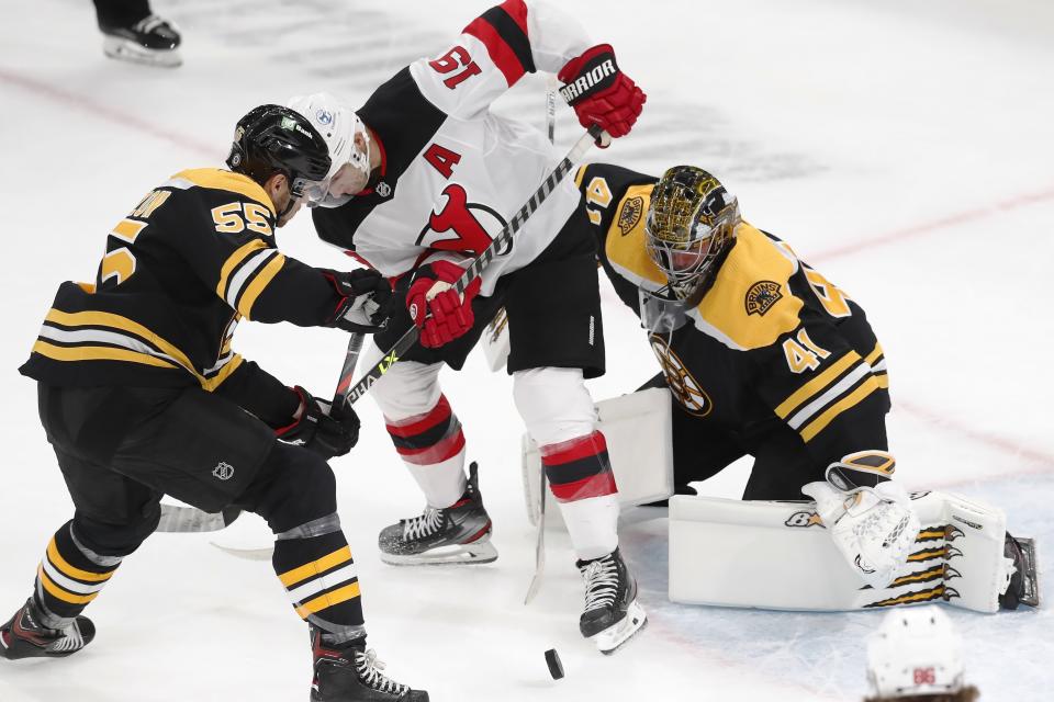 New Jersey Devils' Travis Zajac (19) and Boston Bruins' Jeremy Lauzon (55) battle for the puck in front of Bruins goalie Jaroslav Halak (41) during the second period of an NHL hockey game, Sunday, March 28, 2021, in Boston. (AP Photo/Michael Dwyer)