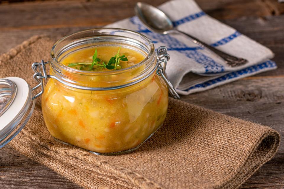 Fresh and homemade cooked soup or stew in a jar served isolated on rustic and wooden table. Closeup view