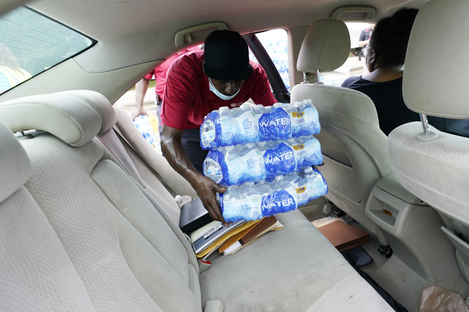 A Salvation Army member places cases of water inside a waiting vehicle in Jackson, Miss., Wednesday, Aug. 31, 2022. The organization and a local Walmart store established a mid-morning distribution site to assist water needy residents. The recent flood worsened Jackson's longstanding water system problems and the state Health Department has had Mississippi's capital city under a boil-water notice since late July. (AP Photo/Rogelio V. Solis)